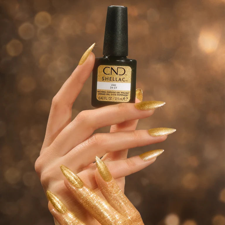 Hand holding a bottle of CND Shellac 24K with gold glitter nails