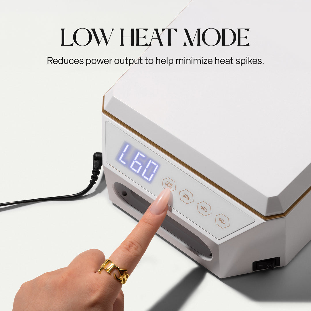 Finger pressing the LOW HEAT button on the Aprés Mini Nova white LED lamp, display showing L60